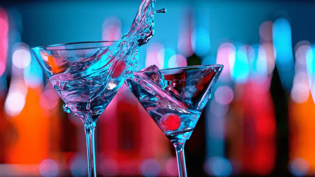 Cocktail glasses with splashing drinks at a vibrant bar in Paddington London nightlife scene.