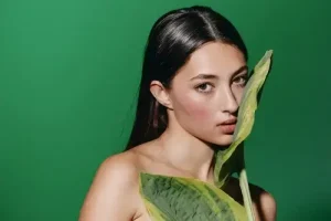 Elegant woman posing against a green background representing the luxury aesthetic of exotic escorts in London